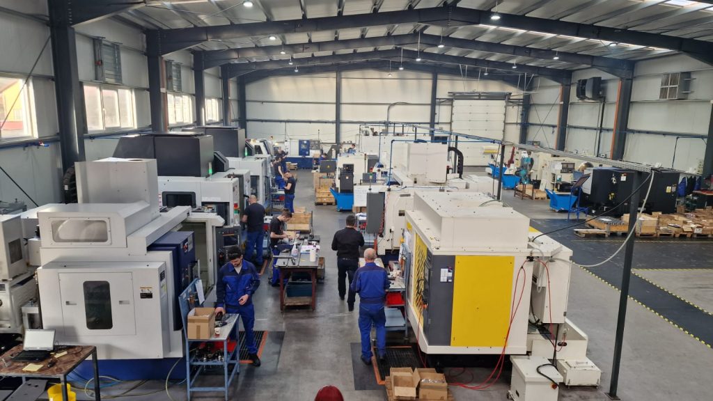 European CNC metal manufacturing facility with multiple CNC machines and production staff