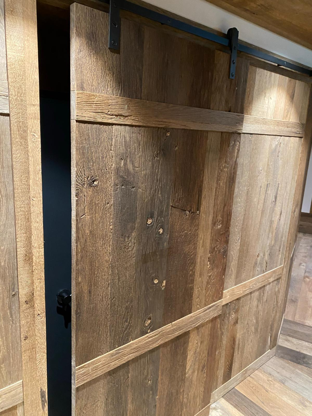 Reclaimed oak barn door with original patina installed in luxury interior