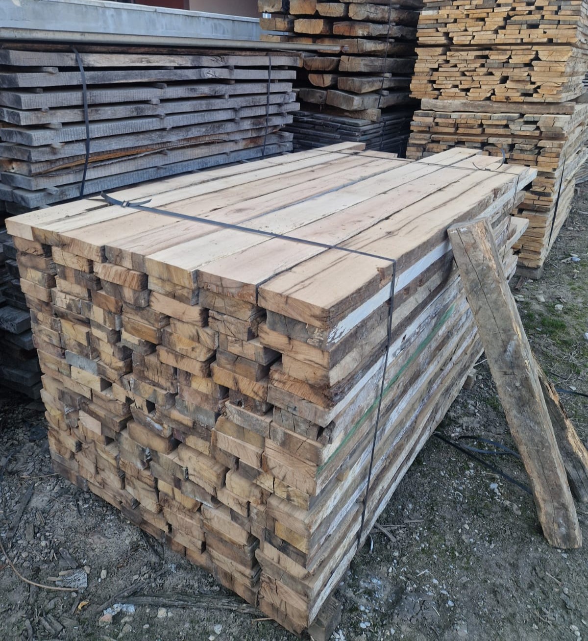 Stacked reclaimed oak planks and beams prepared as raw stock for further processing